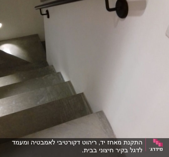 מעקה מתכת שחור על קיר מדרגות לבן
